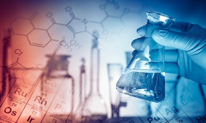 Blue rubber gloves holding a beaker with a periodic table in the bacgkground