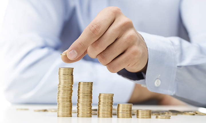 Six stacks of coins decreasing in heights from left to right being stacked by hand